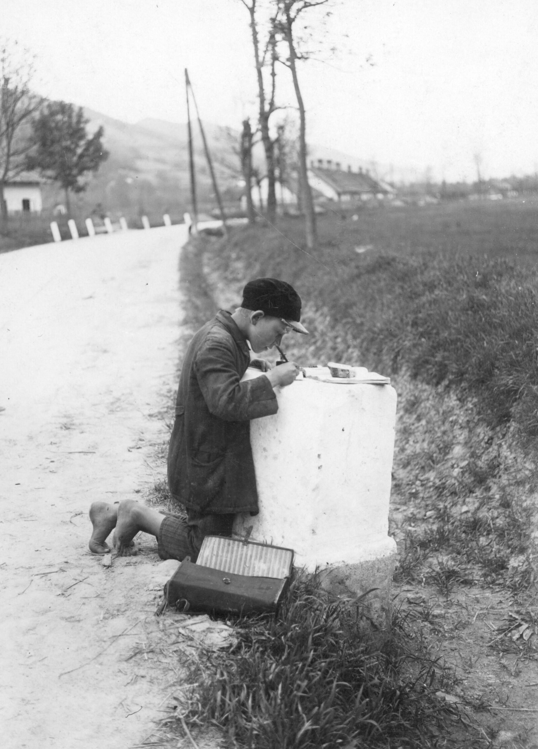 Schoolboy Józef Drożdż does his homework on top of a milestone, Poland, 1931. [2510×3496]