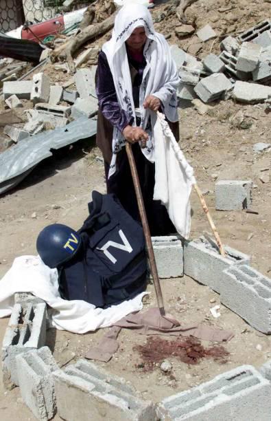 A Palestinian woman points to the bloodstain of British documentary filmmaker James Miller, as his helmet and bulletproof vest lie at the scene where he was fatally shot in the neck by an Israeli sniper while Miller was filming his documentary “Death in Gaza” for HBO. Rafah , May 2003 [612 x 395]