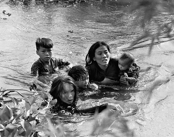 A Vietnamese mother and her children wade across a river, fleeing a bombing raid on Qui Nhon by United States aircraft, Vietnam, September 7, 1965.(612×483)