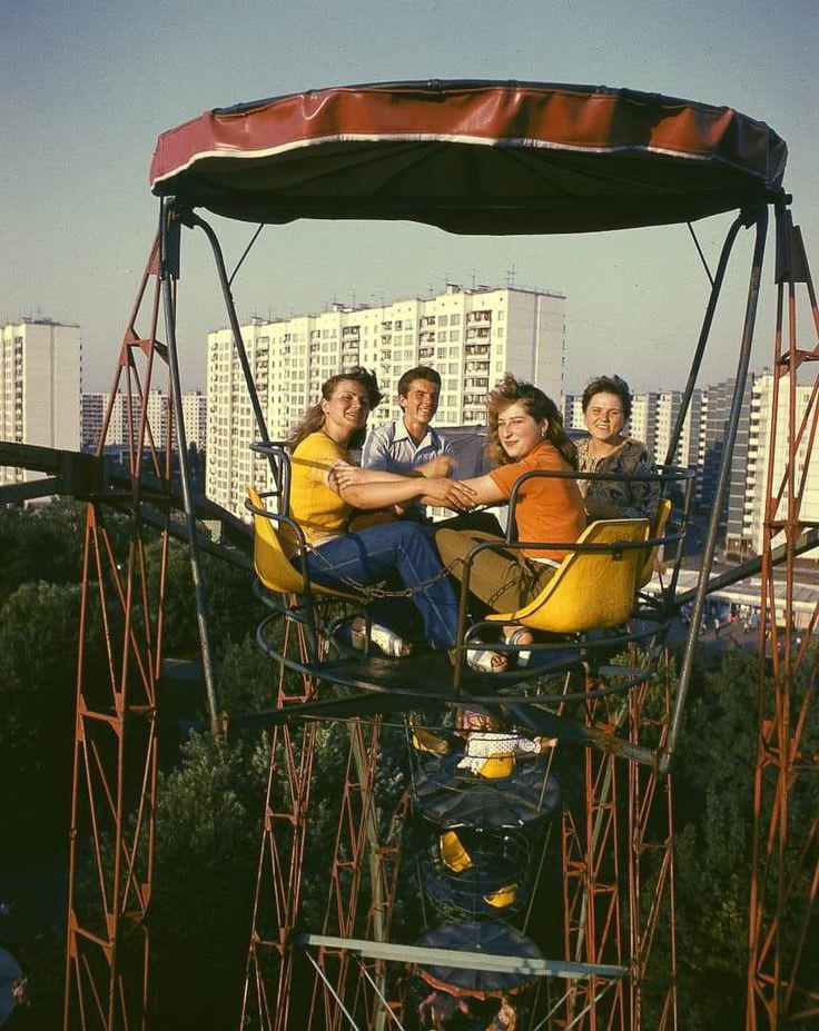Four students on a Ferris wheel, with apartment blocs in the background, on a summer day in Kyiv, Ukrainian SSR, Soviet Union, c. 1986. – Photo was by the Photographer Boris Gradov. [736 x 927]
