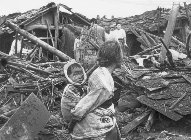An elderly woman and her grandchild wander among the debris of their wrecked home in the aftermath of an air raid by U.S. planes over Pyongyang, the Communist capital of North Korea. 1950 [450 x 612]