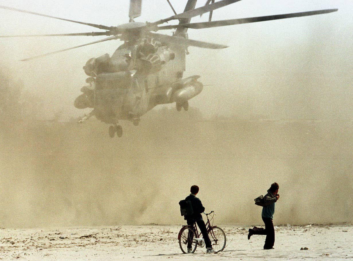 Albanians watch a CH-53 Super Stallion helicopter from the U.S. Marine Corps – take off from Golem beach near the port city of Durres – during the civil unrest in Albania, c. January – August 1997. [1231 x 912]
