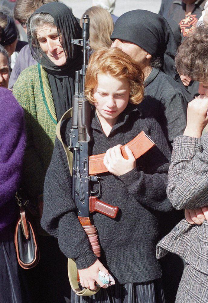 Abkhazian young woman holds a Russian AK-74 assault at a funeral in the town of Gudauta – that rifle belonged to a man who was killed in fighting in Abkhazia, c. September 25th, 1993. [688 x 1000]
