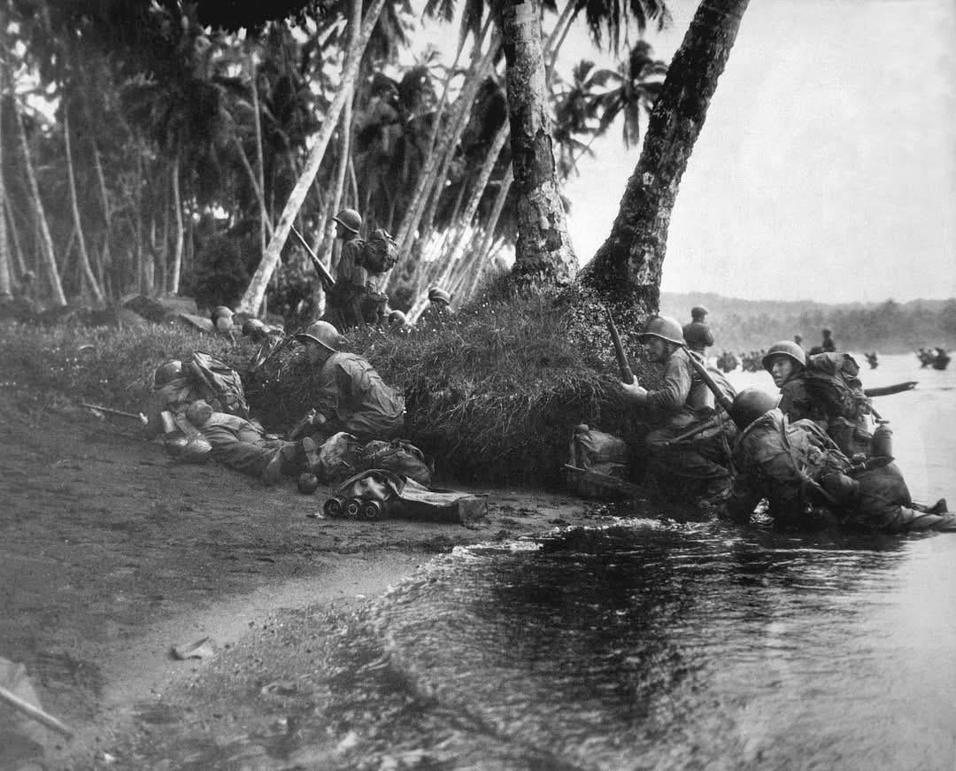 Attacking at the break of dawn in a heavy rainstorm, the first Americans ashore huddle behind tree trunks and any other cover they can find during landing operations on Rendova Island, Solomon Islands, on June 30, 1943. [1080×871]