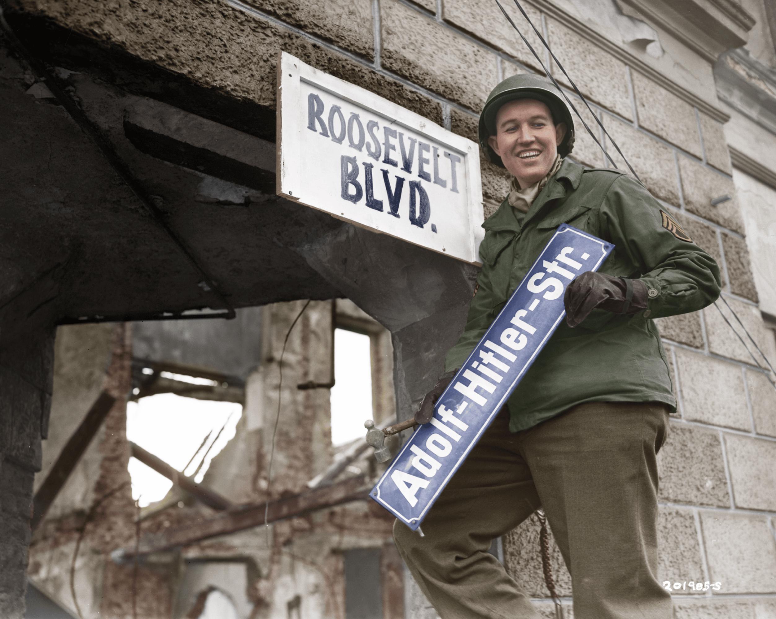Staff Sergeant George A. Kaufman replacing a road sign from ‘Adolf Hitler Str.’ to ‘Roosevelt Blvd.’ in the German town of Krefeld shortly after its capture by Allied forces. The street was later renamed to Rheinstraße. (1945) [2505×2000]