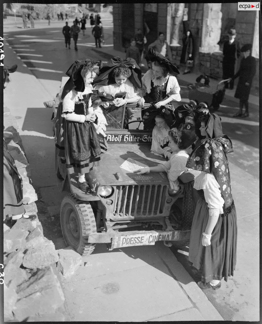 March 1945: Women in Strasbourg gather around a jeep of the Cinematographic Service of the French army. It’s decorated with a German street sign, and the hood is painted with a list of liberated towns and cities the vehicle has passed through. [1036×1080]