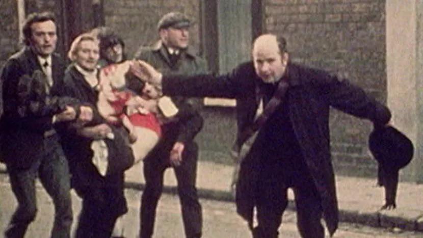 Father Edward Daley leads a group of nationalists to safety during the events of Bloody Sunday in Derry, January 30 1972. He carries a blood stained handkerchief/white flag with the injured 17 year old Jackie Duddy, who later died of his injuries in hospital. (830×467)