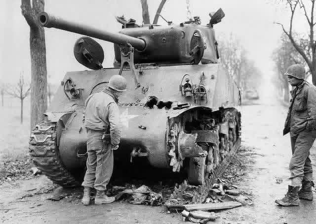 GIs examine multiple frontal penetrating hits on a 14th Armored Division M4A3(76)W Sherman tank knocked out near Barr in Alsace in late 1944 [640×455]