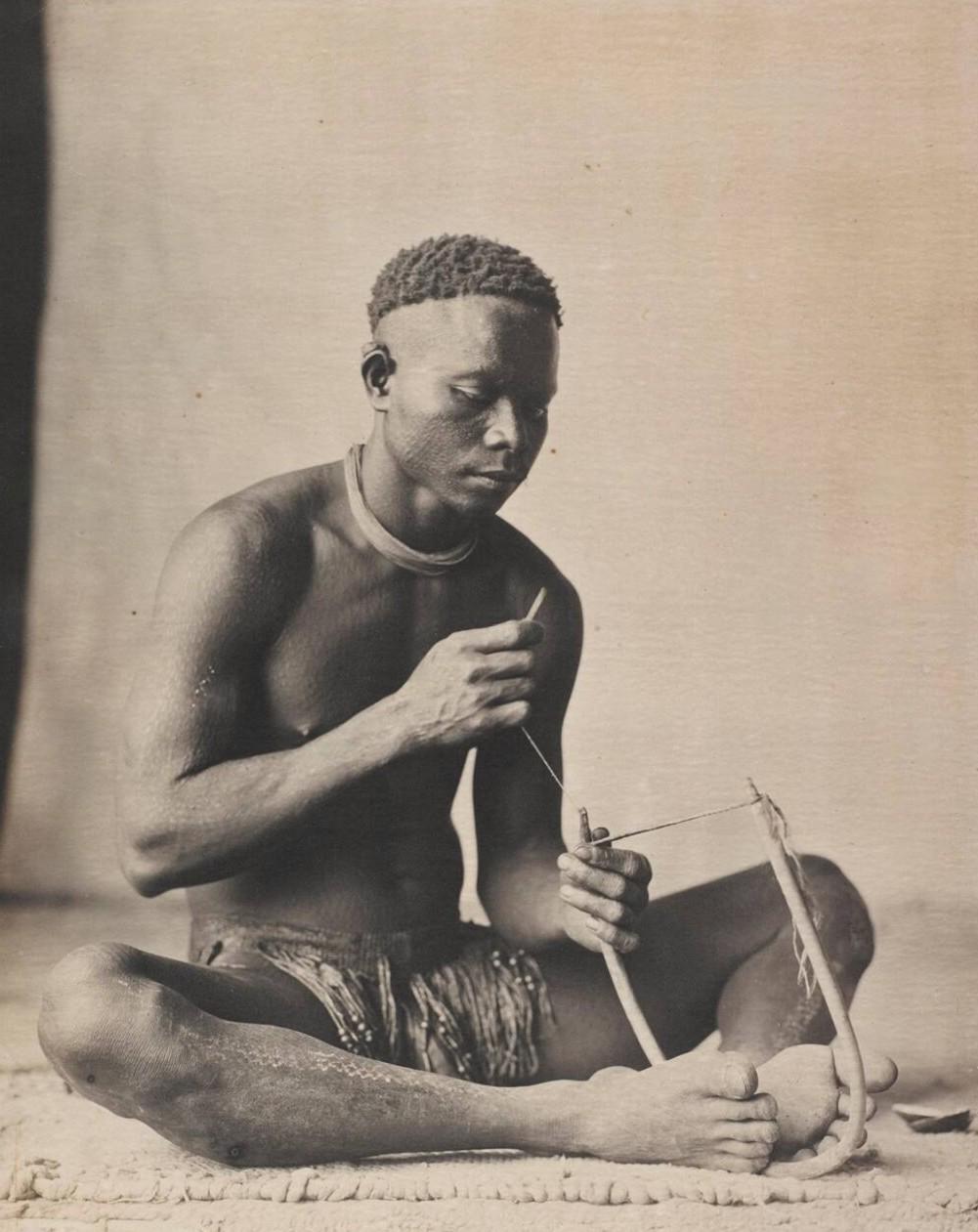 An adult male from the Andaman Islands engaged in crafting a rope or a tool. (1890s) [1001×1261]
