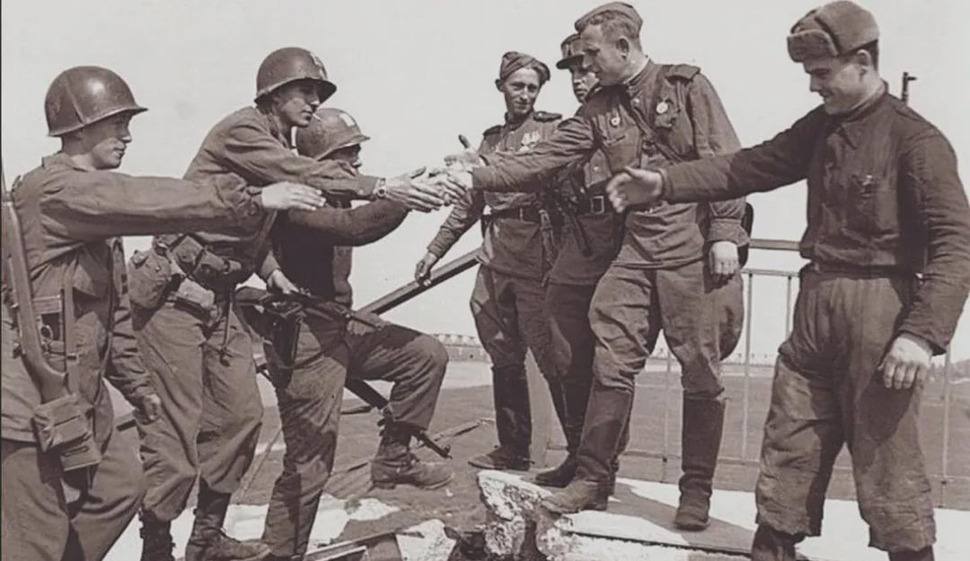 Photo of US soldiers shaking hands with the Soviet soldiers on a damaged bridge at the Elbe River, 1945. [1080×625]