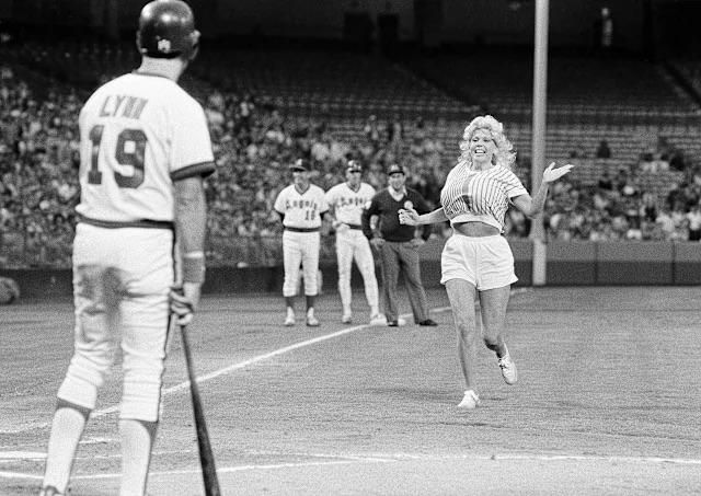Morganna “The Kissing Bandit” running onto the field toward California Angels outfielder Fred Lynn during a game at Anaheim Stadium, Anaheim, California, June 9, 1983 [640×453]