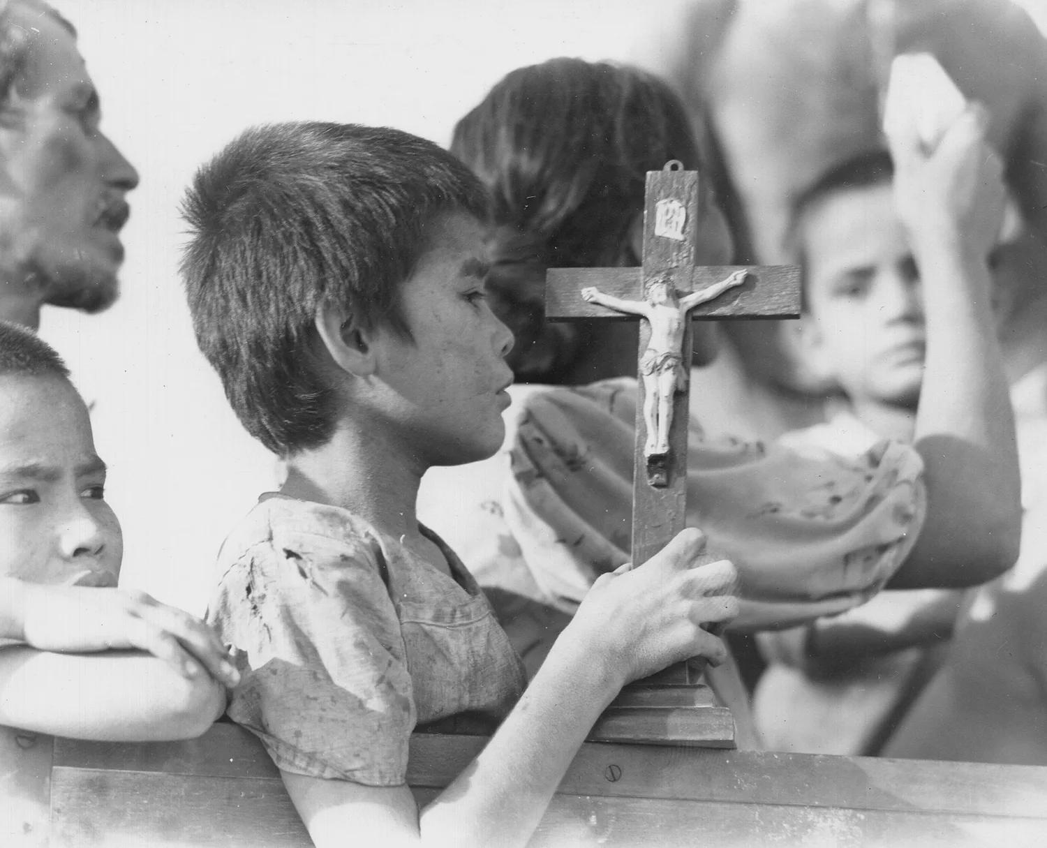 A young Chamorro boy clutches his crucifix as he rides to a civilian interment camp during the battle of Saipan, July 1944. USMC photograph [1500×1215]