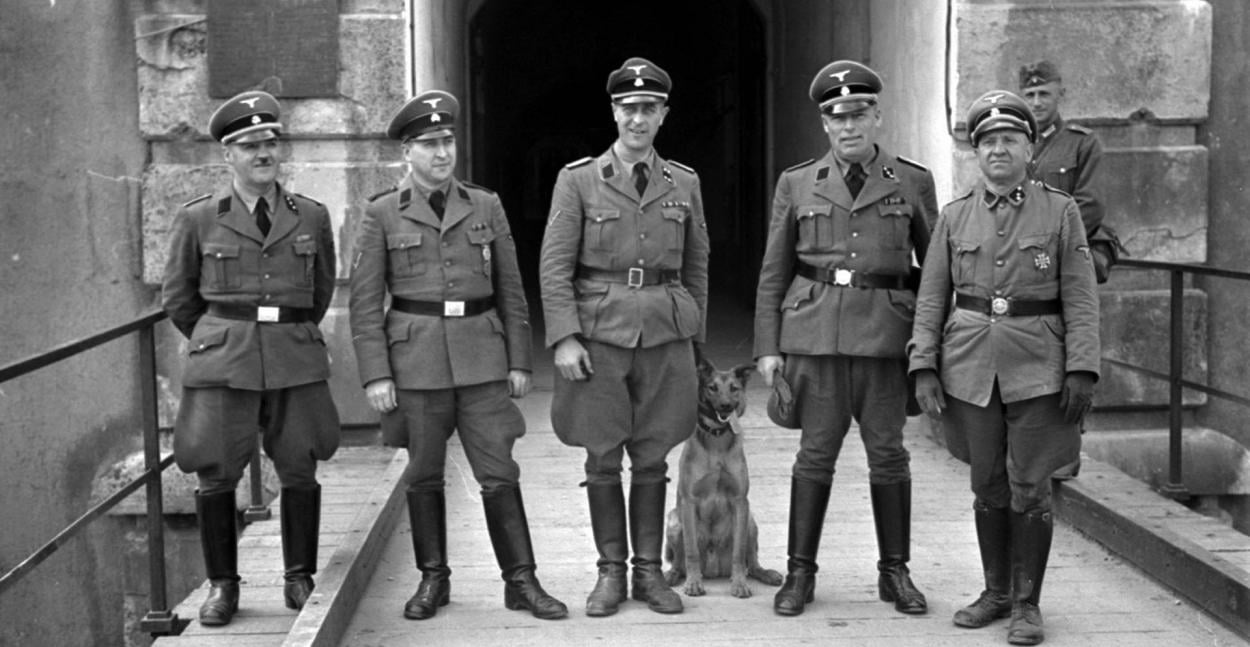 SD-officers posing in front of the entrance gate of Auffganglager Breendonk, Belgium. Taken by Otto Kropf, 1941. [1250×647]