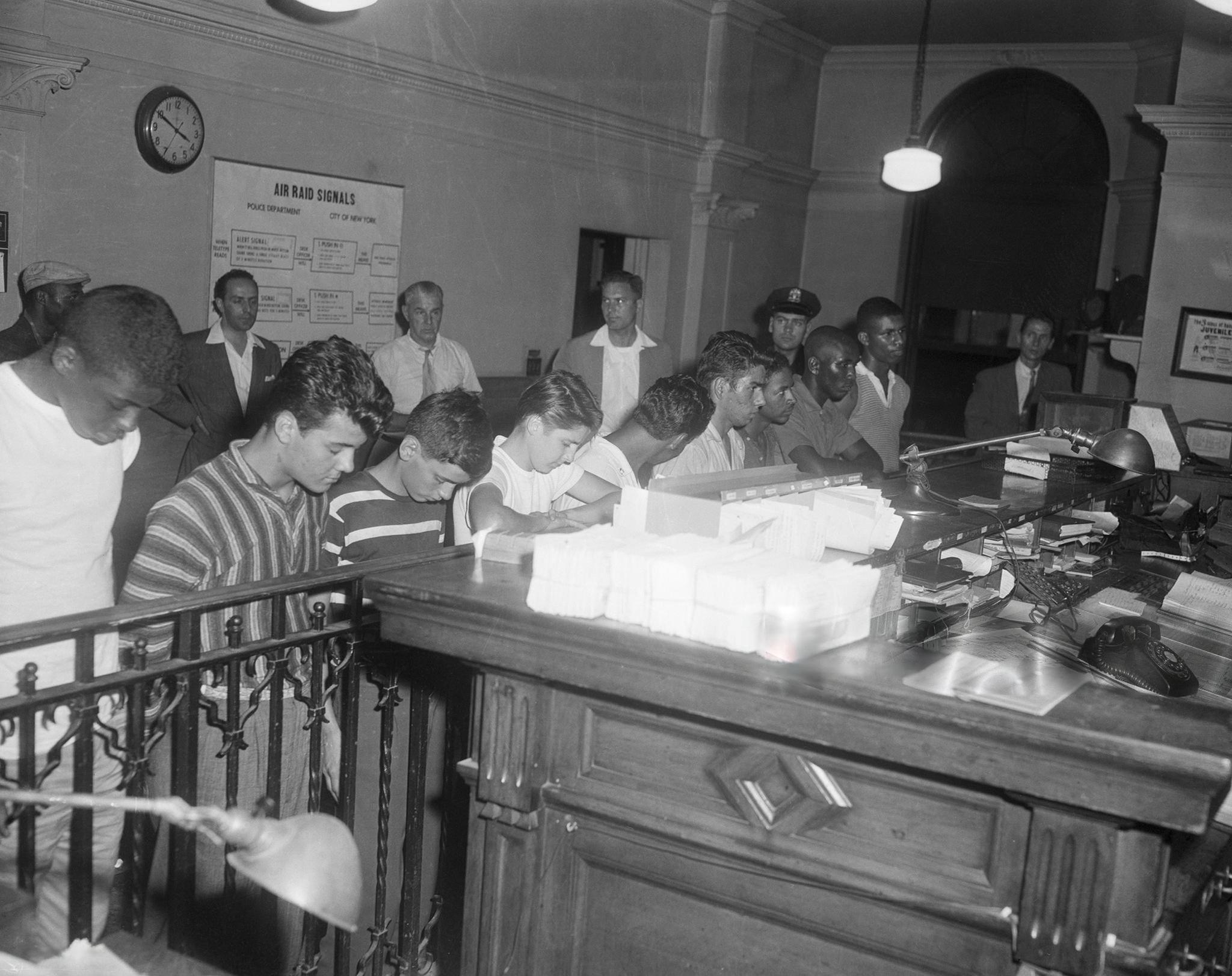 Nine gang members, ranging in age from 15 to 18, are arraigned for the murder of Michael Farmer, a 15-year-old boy whom they and eleven other gang members, ranging in age from 13 to 14, beat and stabbed to death after mistaking him for a rival gang member (New York, 1957) [2048 x 1622].