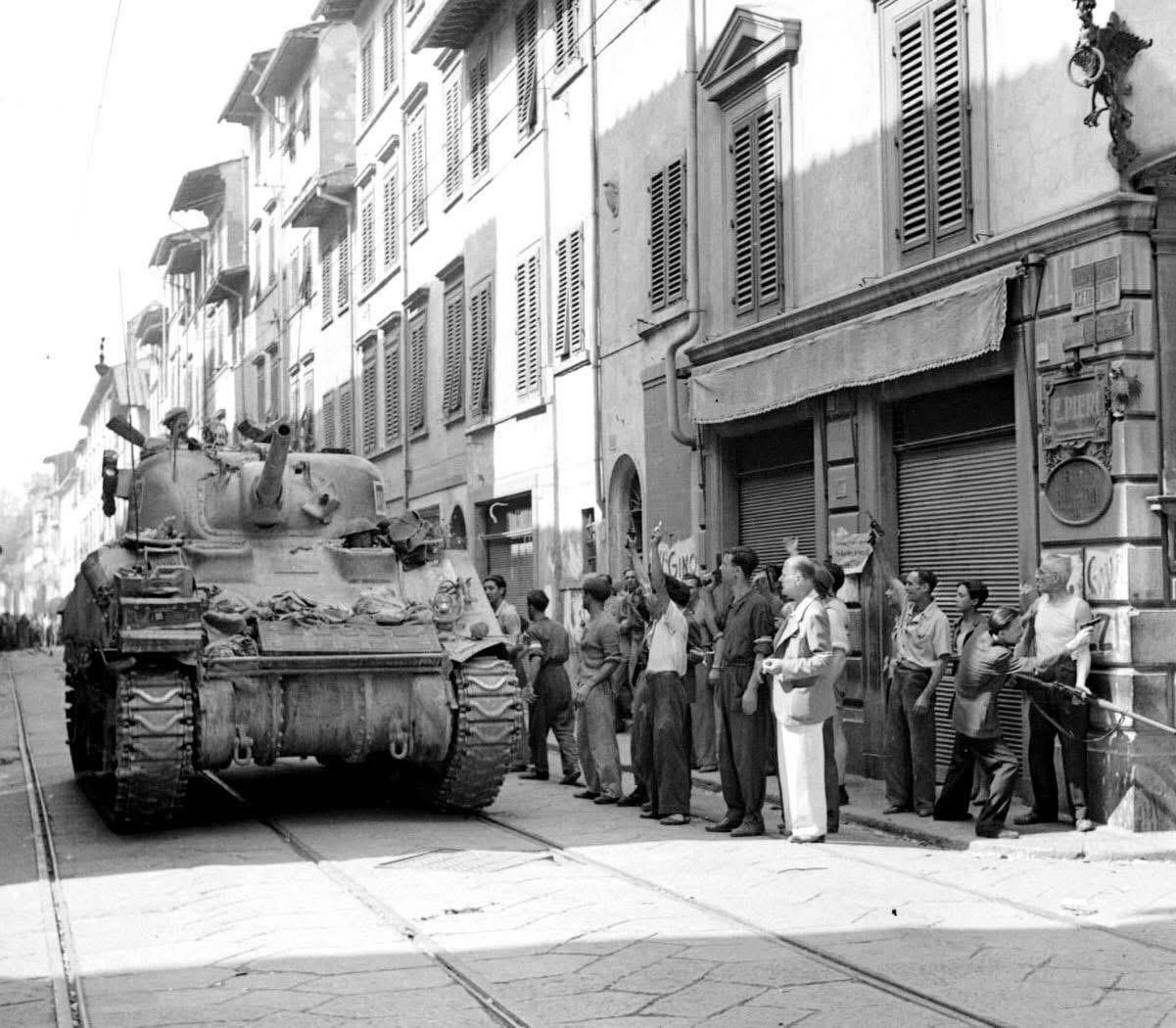 Italian partisans celebrate mid-shootout as a South African 6th Armoured Div. tank rolls forward to help deal with a German sniper’s nest. Florence, Italy, 4 October 1944. [1201×1050]