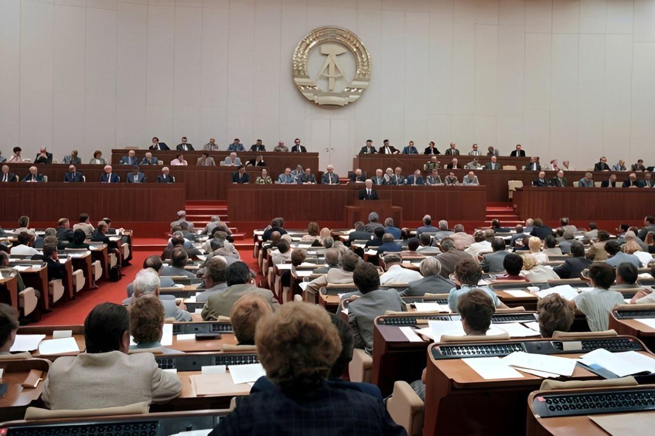 Willi Stoph, Chairman of the Council of Ministers of the GDR, speaking at the lectern in the plenary hall of the Palace of the Republic – behind him, on the bench, were officials of the Socialist Unity Party during a session of the Volkskammer, East Germany on June 30th, 1988. [1280 x 852]