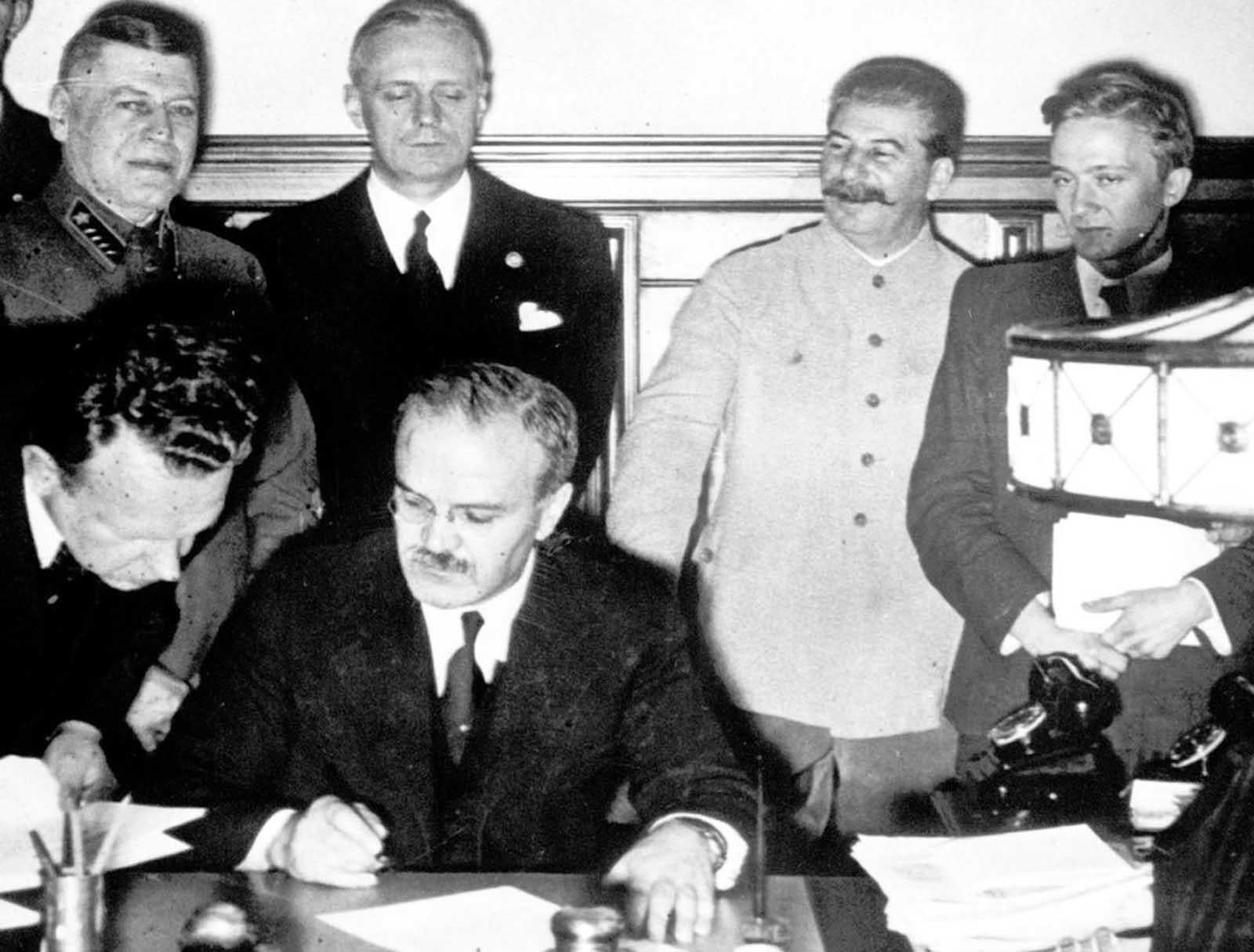 Stalin smiles while Vyacheslav Molotov signs the non-aggression pact with German Reich (August 23 1939). [1600×1215]