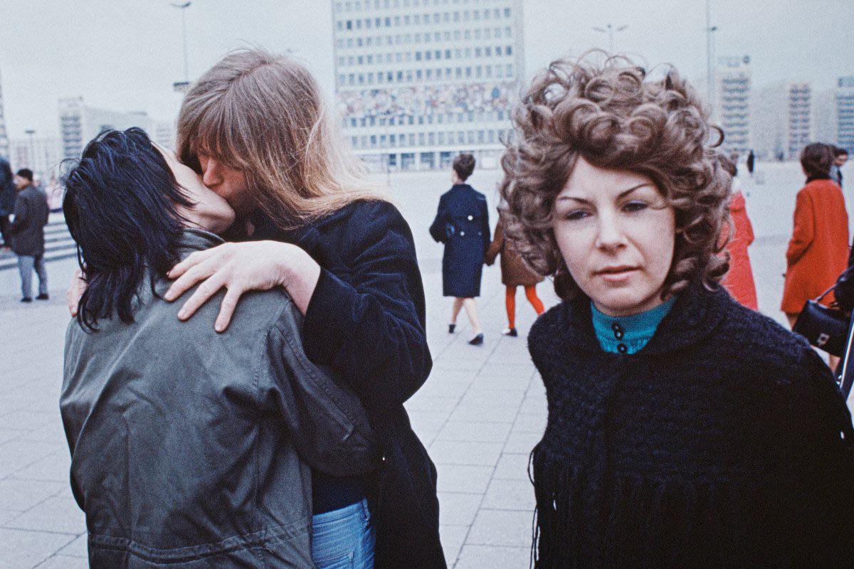 A kissing couple, and a woman looking at the camera – at Alexanderplatz in East Berlin – in the German Democratic Republic (GDR), c. 1972. The photo was taken by the German photographer Thomas Hoepker. [1200 x 800]
