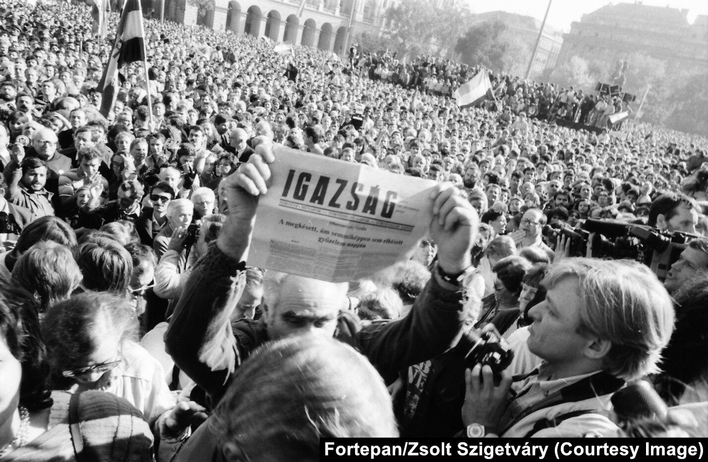 A man holds up a newspaper proclaiming Hungary becoming a democratic republic on 23 October 1989 [1428×933]