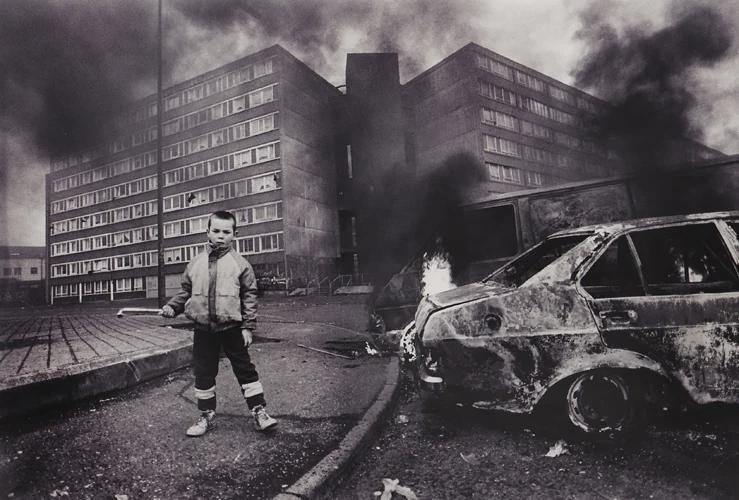 Child with a burnt-out car, Divis Flats, Belfast, Northern Ireland, 1980s. [739×500]