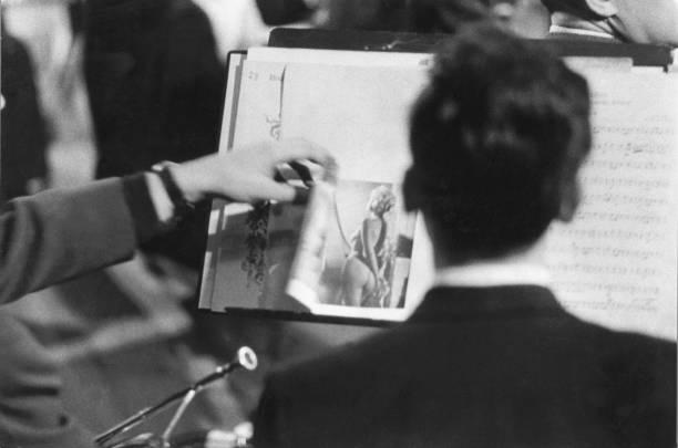 Musicians with the Belgrade Philharmonic place a pin up girl next to their sheet music. January 1st 1962 (612×410)