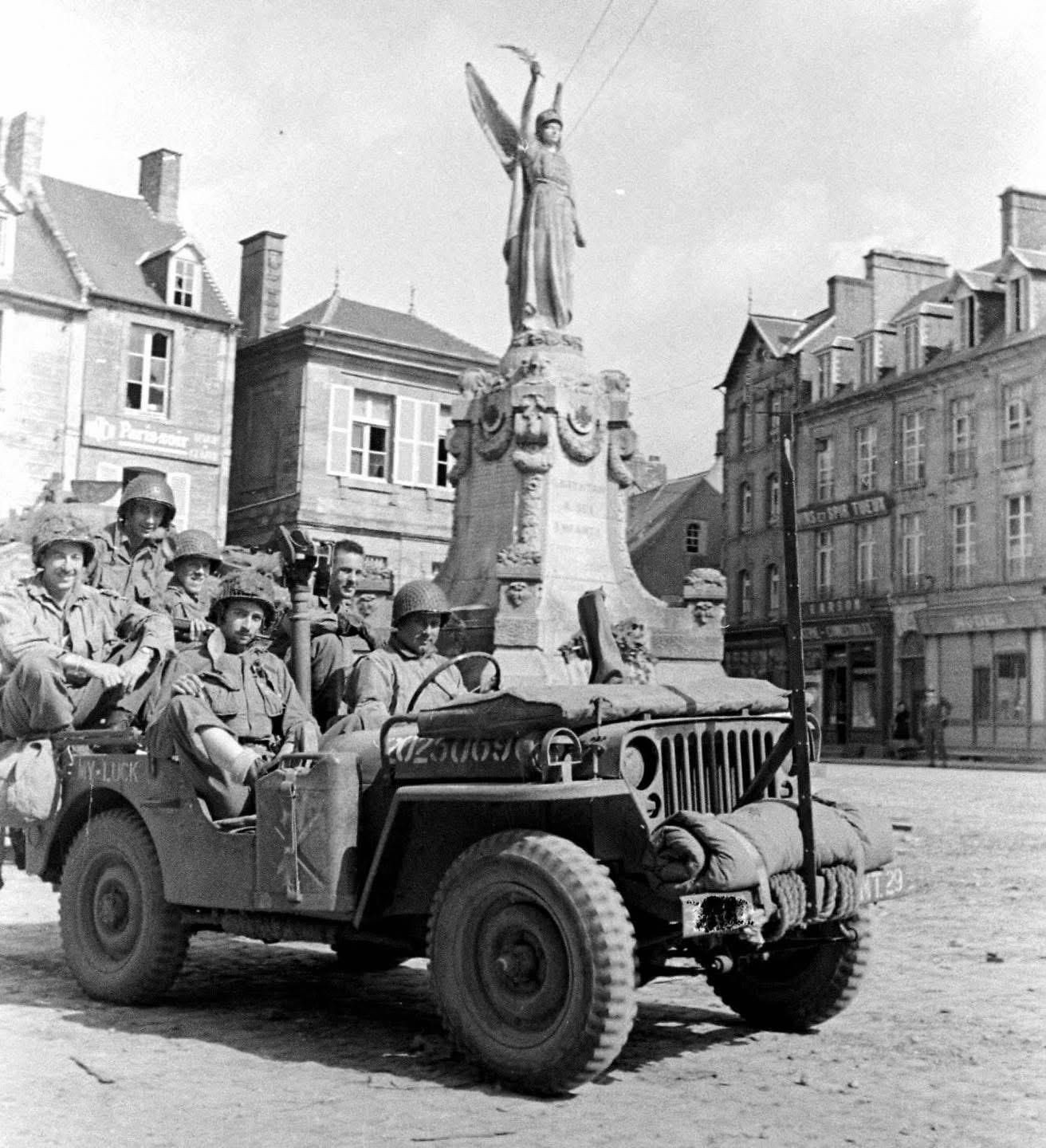 101st Airborne Soldiers in a Jeep at “Place De La République” in Carentan, Normandy, June 1944. Note the “anti-decapitation” bar modification on the front of the Jeep to protect occupants from the wire booby traps that the Germans often stretched across roadways. [1312×1440]