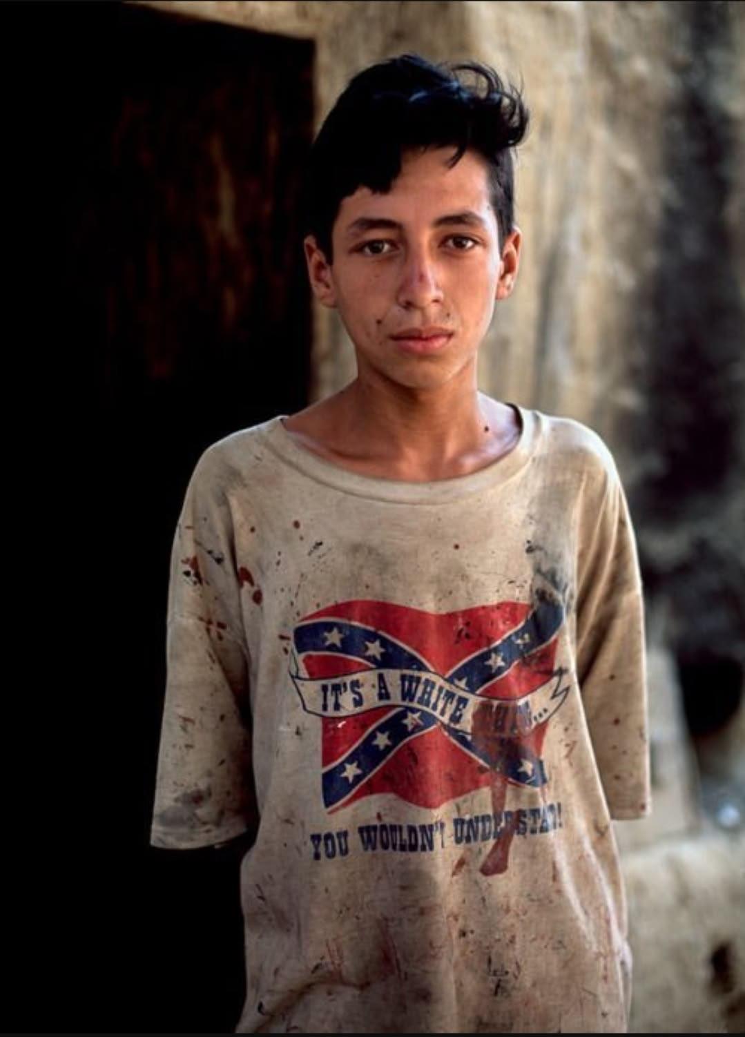 A young boy in northern Afghanistan photographed wearing a shirt with the Confederate flag, 2002 (1079×1502)