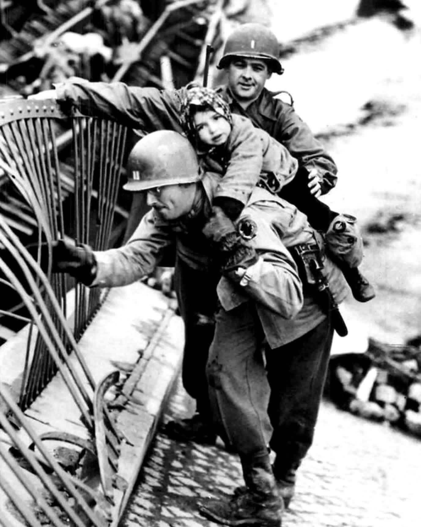 U.S. Army Cpt. J. McMahon and an unidentified American soldier of the Ninth U.S. Army carry a small German girl across the destroyed bridge at Tangermünde over the River Elbe in May, 1945. [1377×1721]