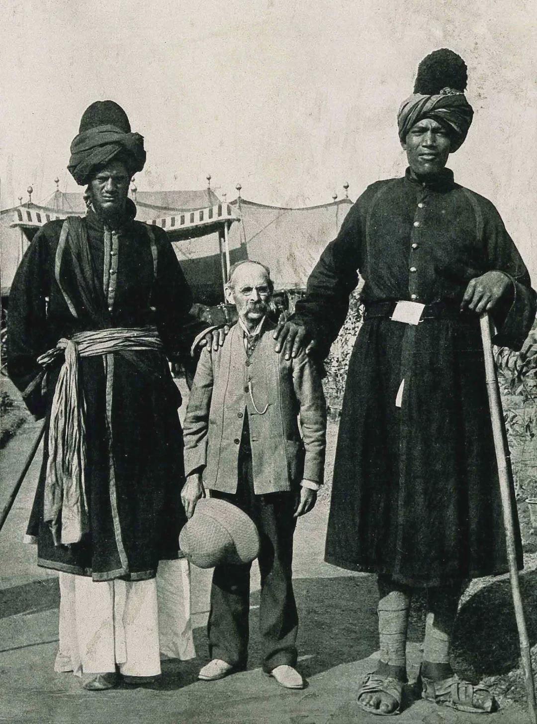 A photographer standing between two very tall Kashmiri guards at the Delhi Durbar, 1903. [1080×1455]