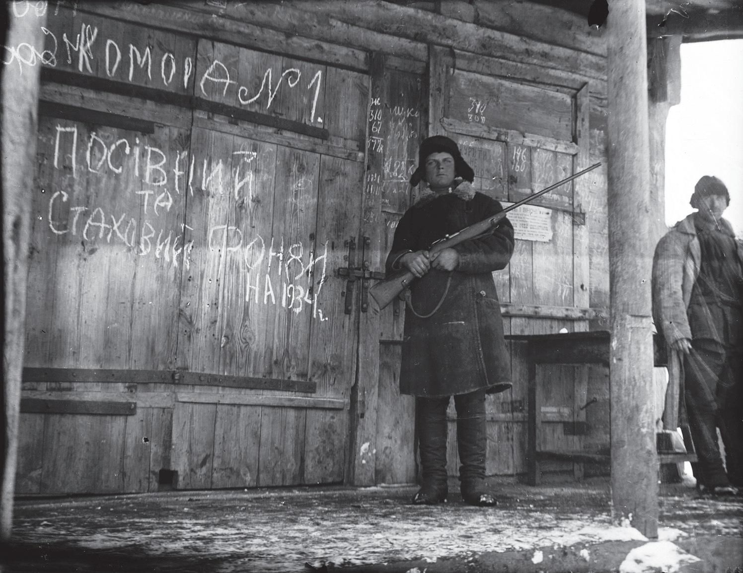 Kharkiv, Ukraine.  1932-33.  An armed man stands guard at the door of a grain storage facility during the Holodomor.  The writing on the door reads, “Storehouse N. 1” and below it, “Seed and insurance funds for 1934.”  [1496 x 1155]