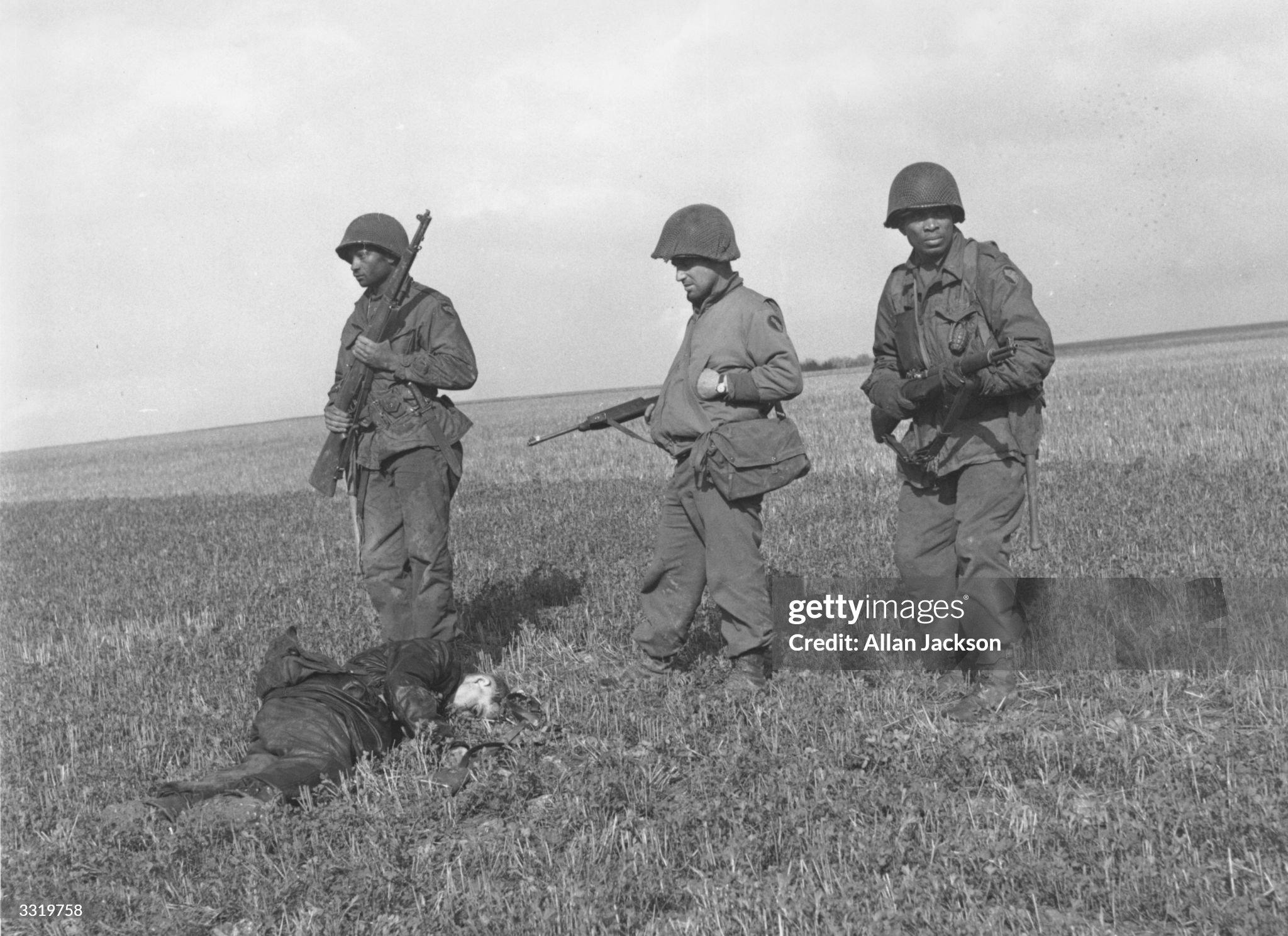 Two Black-American infantrymen of the 104th First Army Division with their captain, stand alert over the body of an SS trooper they killed as he ran across the field. Germany, 4/17/1945.[2048 × 1489]