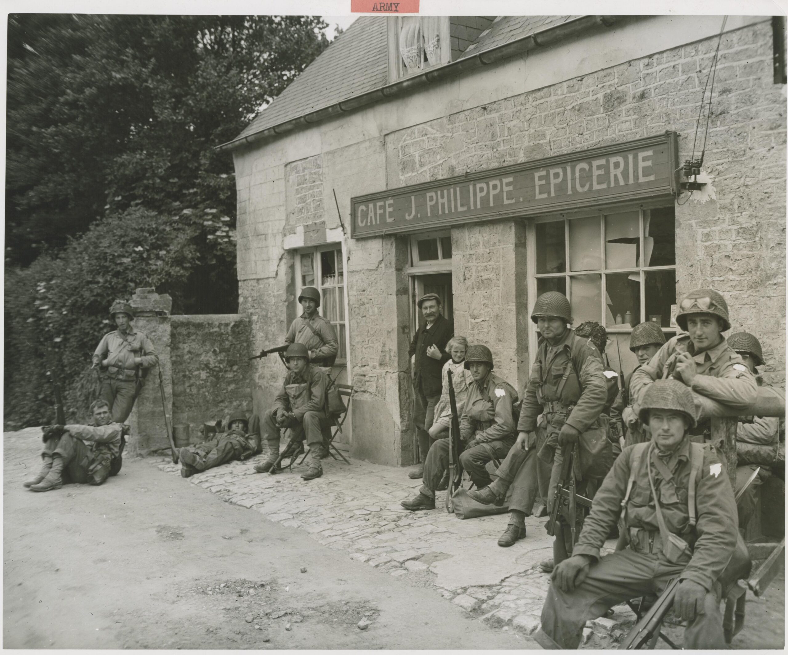 Exhausted from their rapid advance inland from the Normandy beachhead, U.S. soldiers relax for a few minutes outside a French cafe. 20 June, 1944 [3600 × 2994]