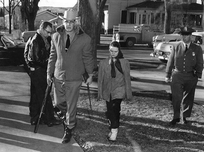 Caril Ann Fugate, 14, is taken into custody by Deputy Sheriff Bill Romer (left) and Police Chief Bob Ainslie (right). She and Charles Starkweather, 19, were captured after a high speed chase. Fugate was charged as an accomplice to Starkweather, who murdered 11 people (Wyoming, 1958) [505 x 679].