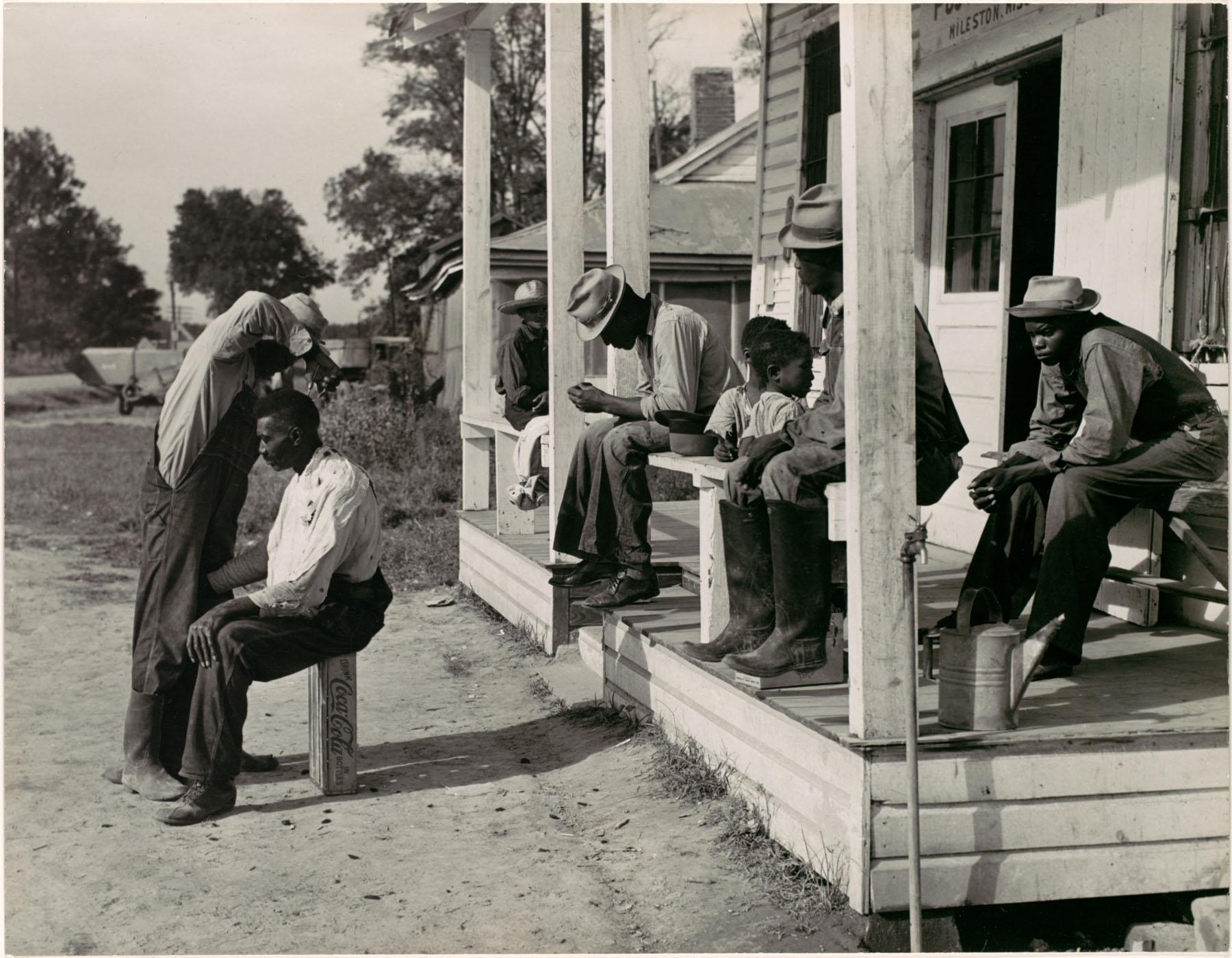 Haircutting in front of plantation store after being paid off on Saturday, Mileston Plantation, Mississippi Delta 1939.[1800×1399]