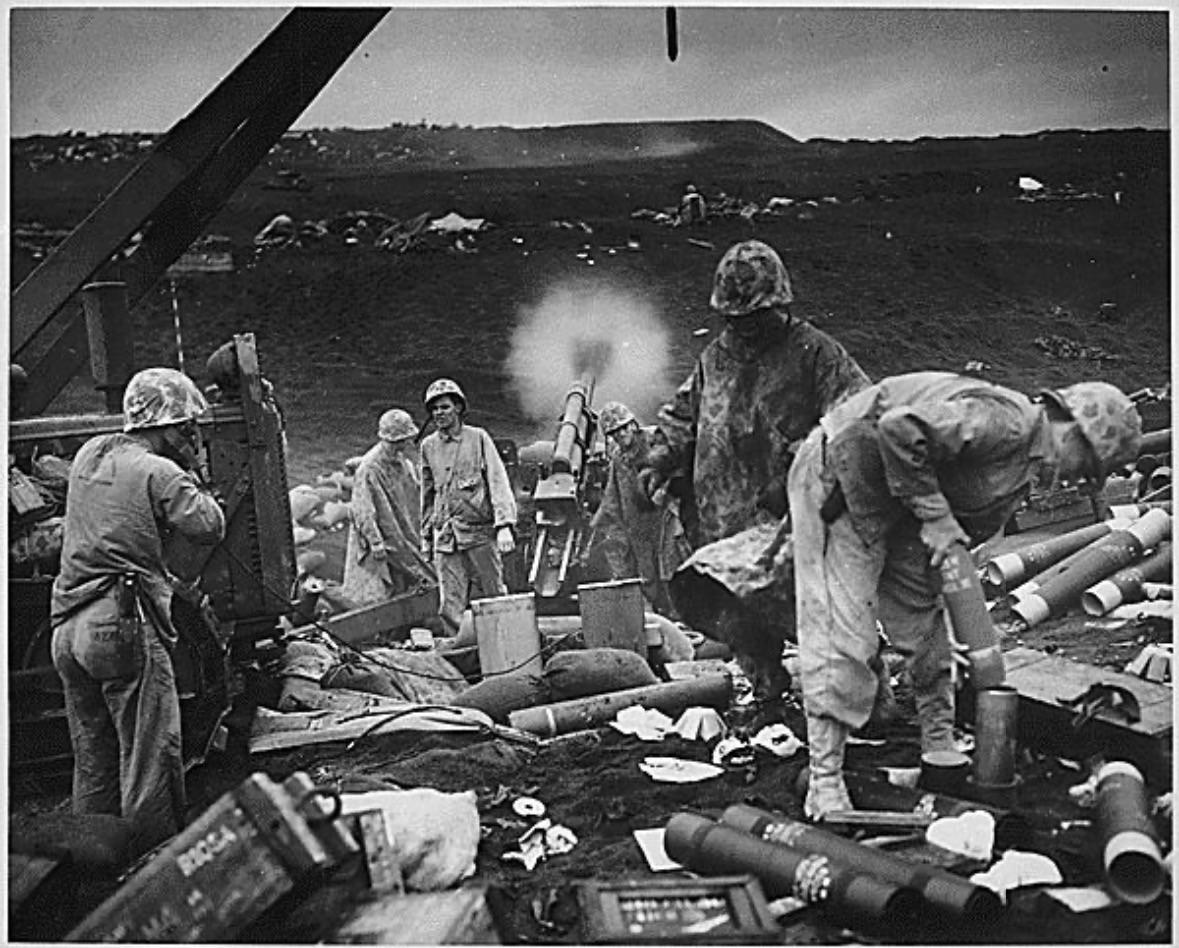 “Across the litter on Iwo Jima’s black sands, Marines of the 4th Division shell enemy positions cleverly concealed back from the beaches. Here, a gun pumps a stream of shells into positions inland on the tiny volcanic island.” February 1945. [1179×948]