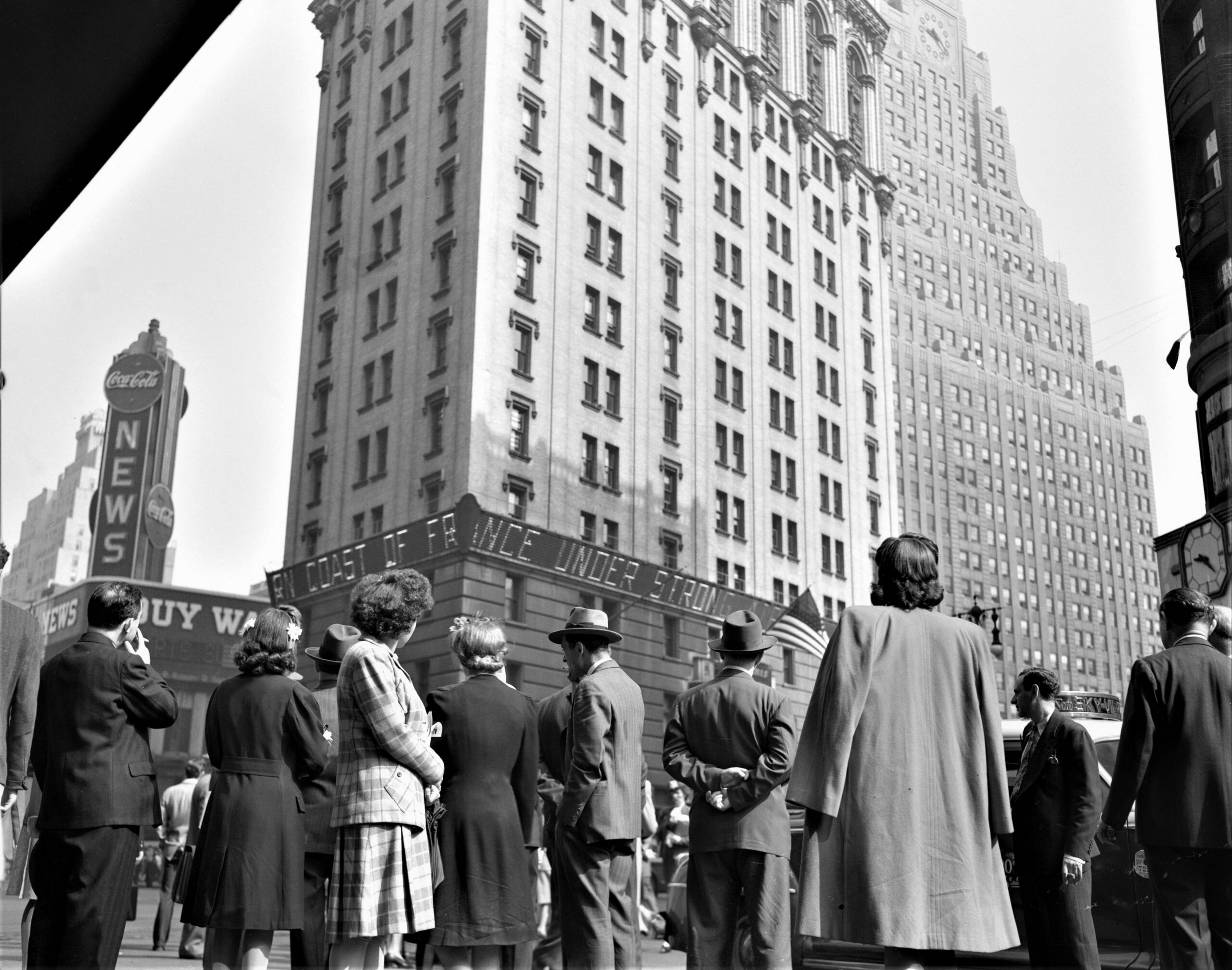 Pedestrians in New York City watching news of the Normandy Invasion on an electric marquee near Times Square on D-Day, June 6, 1944 [3482 × 2743]