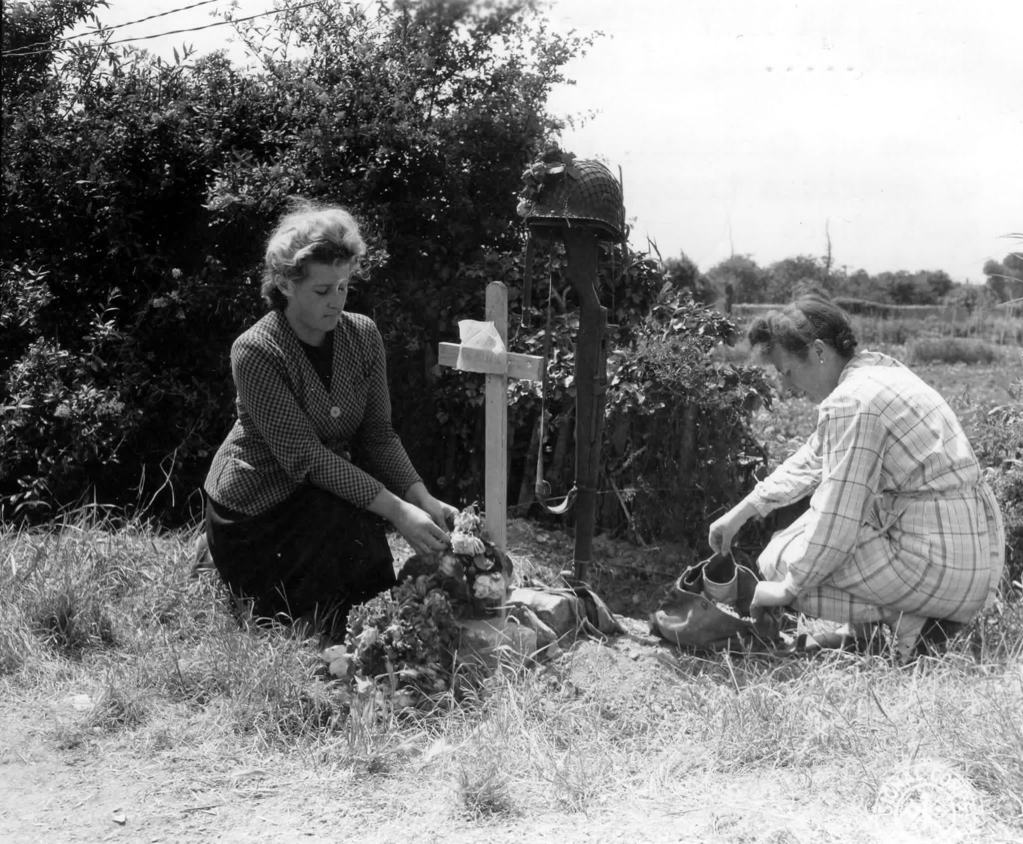 Women of Carentan, France, recently occupied by American troops, place flowers at a spot where an American paratrooper died. His helmet, gun and gasmask mark his grave as does a cross with the notation, “Mourt Pour La France”. 19 June, 1944. (Signal Corps photo and caption) [2048×1690]