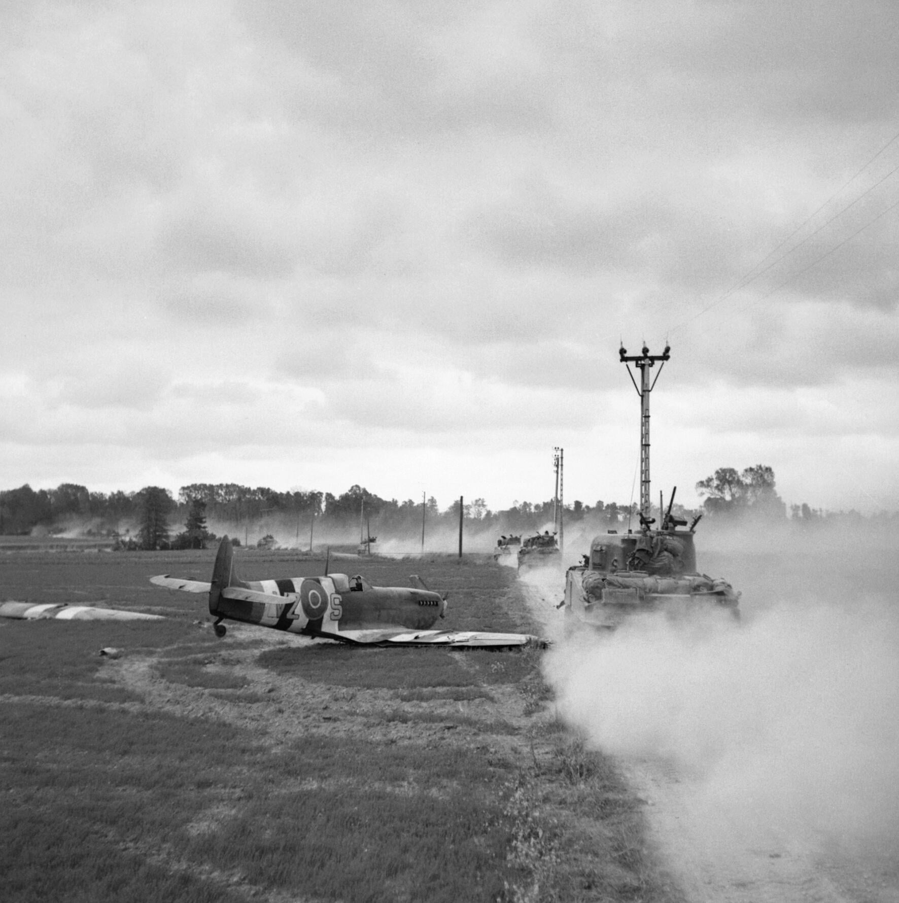 British Sherman tanks move up past a crash-landed Royal Canadian Air Force Spitfire for an attack on Tilly-sur-Seulles, Normandy, France. 17 June 1944. [1772 × 1780]