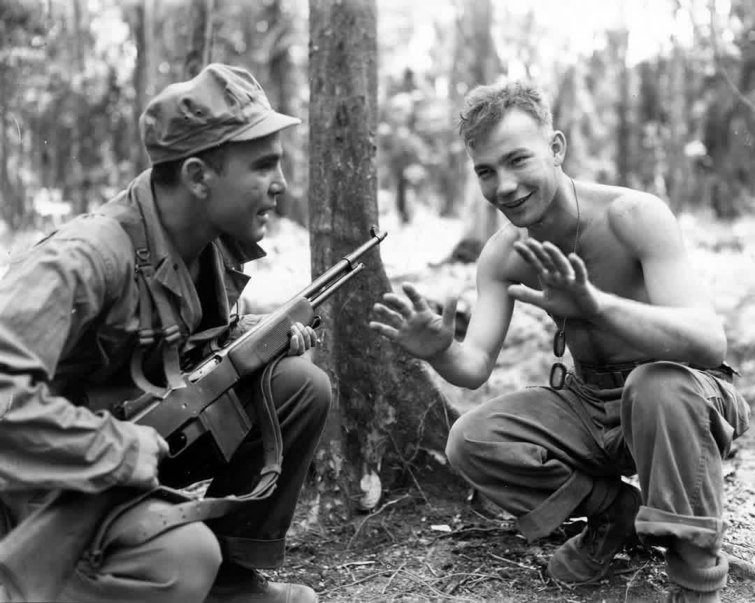 Pfc. Joseph Piano, left, Waltham, Mass., relates his experiences on Hill 260 on Bougainville, where he killed 10 Japanese, to Pfc. Fred Love, 11A Menahan St., Brooklyn, NY. Both men are members of the 23rd Infantry Division. March, 1944. [1080×862]