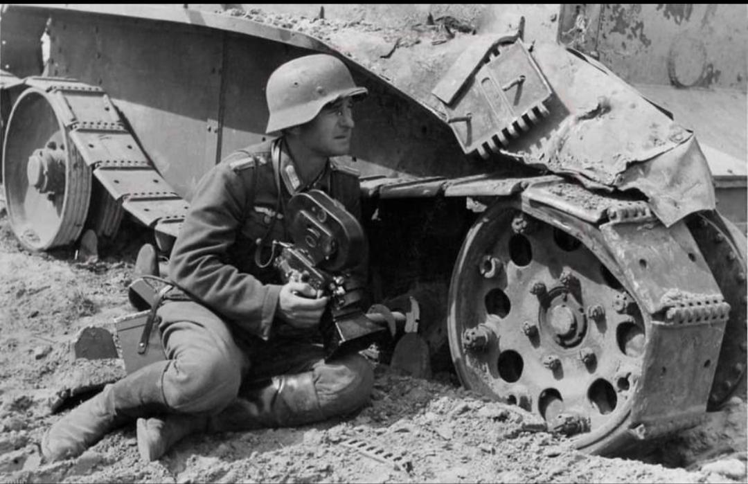 A German Kriegsberichter (war correspondent), Arriflex in hand documents Operation Barbarossa from behind the cover of a knocked-out BT-5 Soviet light tank. 1941 [1,080 x 699]