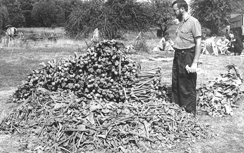 Historian Leon Popek standing next to the remains of Polish civilians exhumed from a mass grave in a former village of Ostrówki (now in Ukraine). On 30 August 1943, members of the Ukrainian Insurgent Army murdered unarmed 438 Polish civilians there, Ostrówki, August, 1992 (800×500).