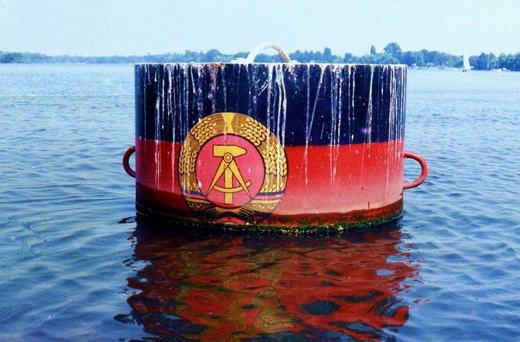 East German border buoy (with the flag of the official state emblem – a hammer and compass with a rye wreath) – on the Havel River near Potsdam, in the German Democratic Republic (GDR), c. 1989. [736 x 485]