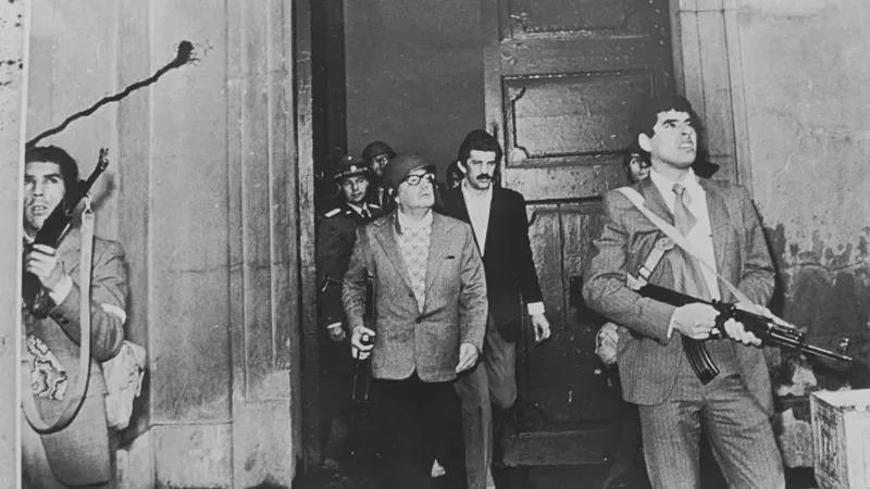Chilean President Salvador Allende, rifle in hand and wearing a helmet, during the attack on La Moneda Palace, 1973. [800×450]