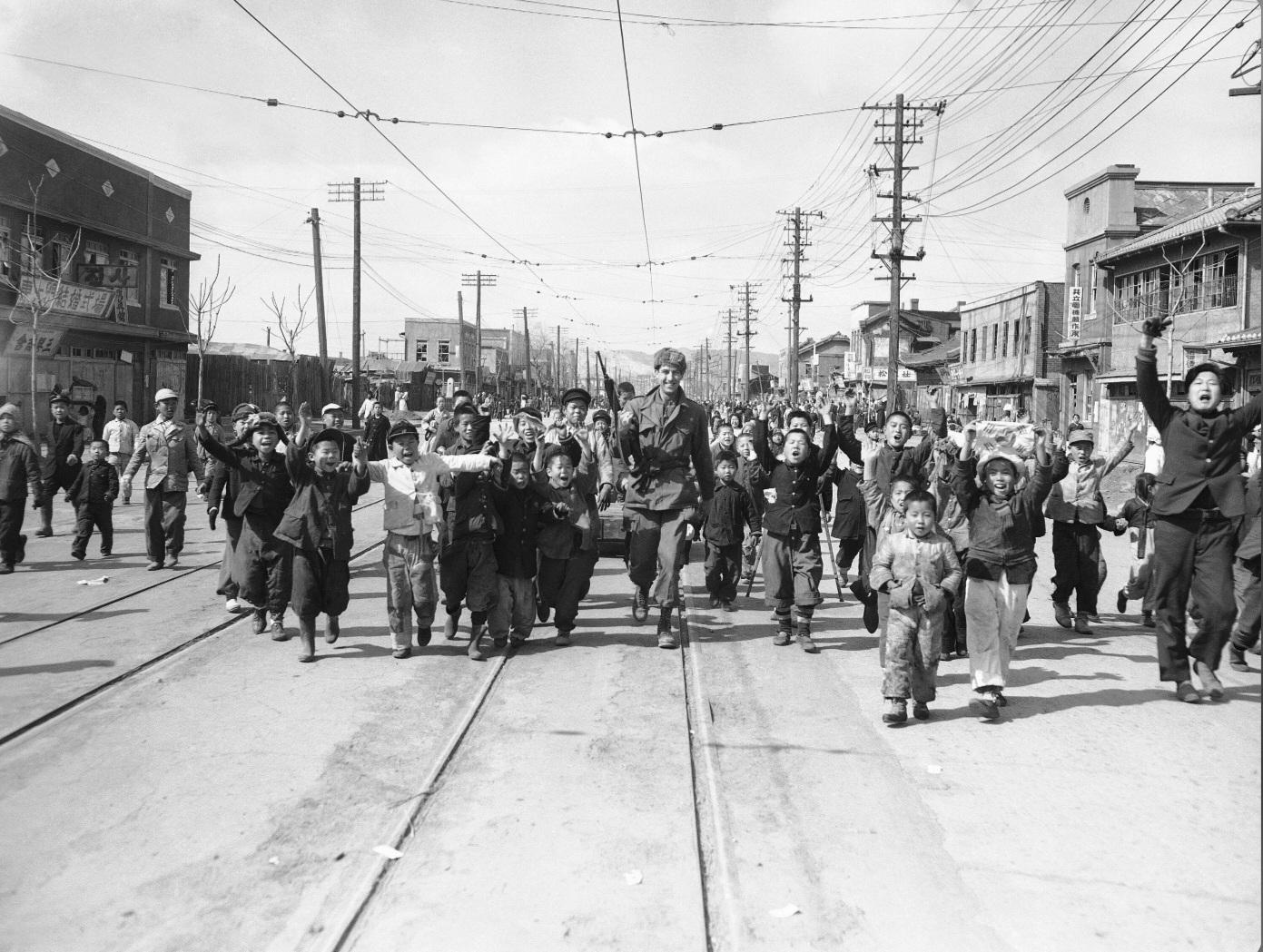 Cheering children surrounding a U.S. soldier as he walks down a street in Seoul, following the re-entry of U.N. troops into the South Korean capital after fierce fighting to recapture the city from communist forces during the Korean War. (1950) [1391×1049]