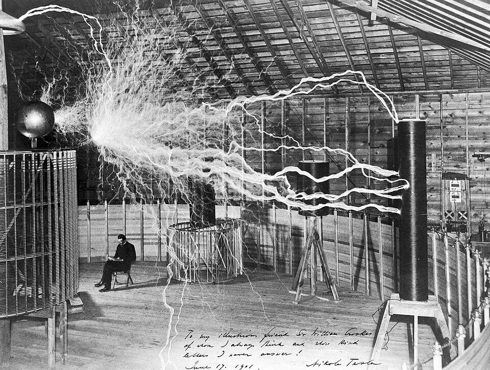 Nikola Tesla sitting in his Colorado Springs laboratory next to his “magnifying transmitter” high-voltage generator, 1899. [960 × 725]