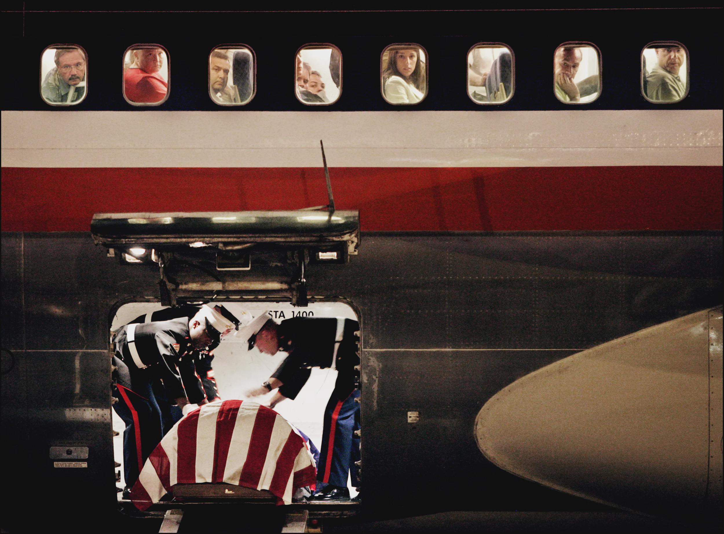 US Marines in the cargo hold of a commercial plane at the Reno-Tahoe Airport, preparing the coffin of 2nd Lt. James J. Cathey, killed by an IED after only one month in Iraq during Operation Iraqi Freedom, to descend on the luggage conveyor belt to his family. August 2005. [2500 × 1845]