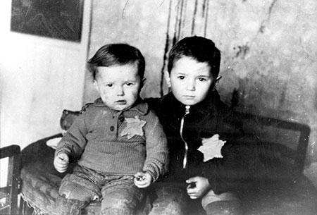 Two brothers, seated for a family photo in the Kovno ghetto in Lithuania. Shortly after this photo, the two boys were deported and did not survive the Holocaust (1944) [450 x 305]