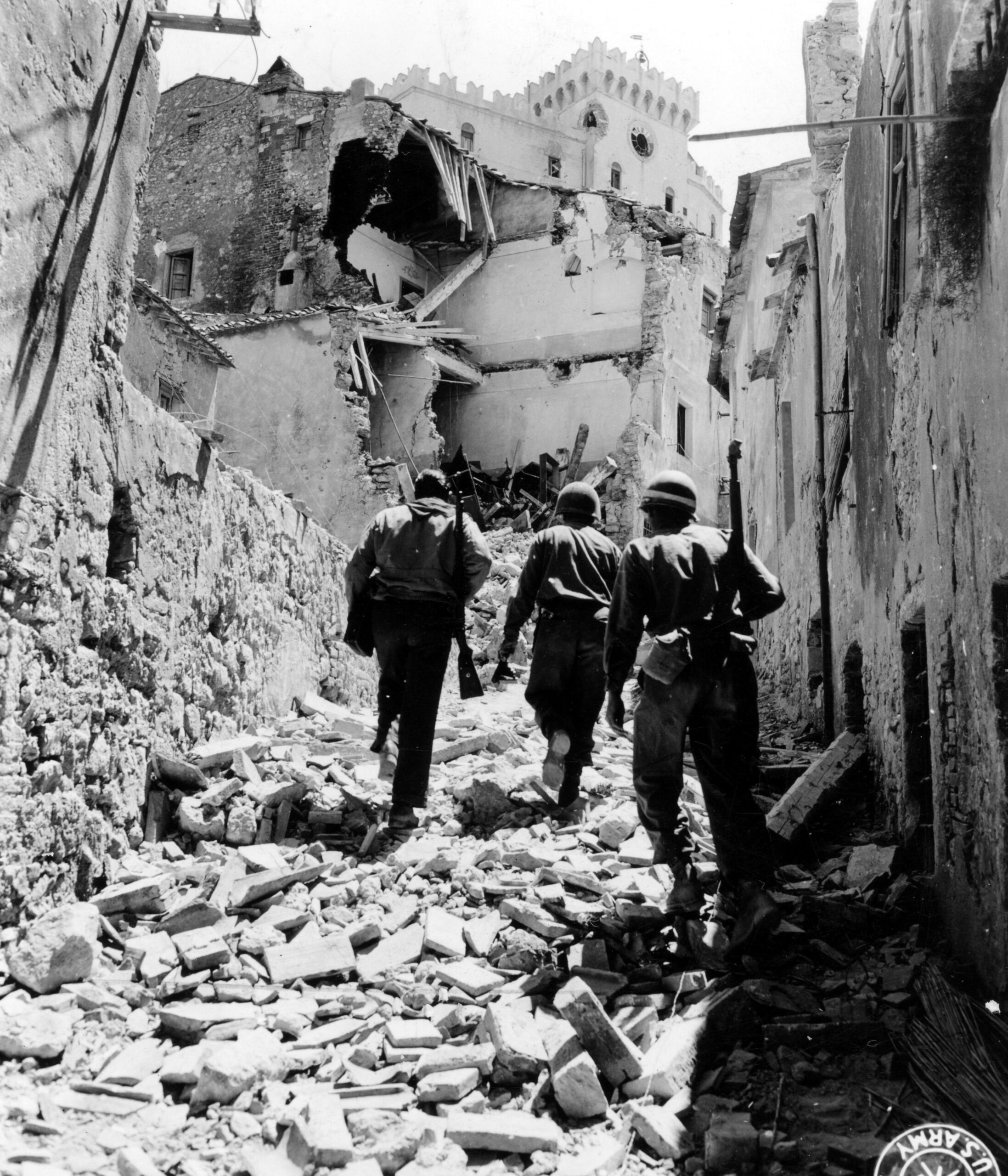 U.S. Soldiers from the 34th Infantry Division walk up a rubble filled street in Rosignano Marittimo, Italy with an Italian partisan. 13 July, 1944 [4095 × 4775]