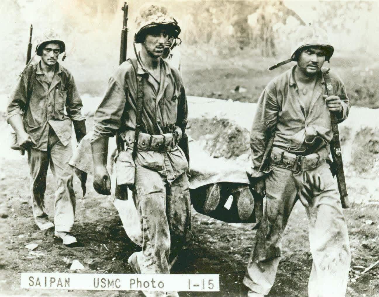 Four United States Marines carrying the covered body of a dead Marine on a stretcher. Official caption on back: “Bringing a dead Marine back from the front. Marine Corps Photo 1-15.” Saipan, Mariana Islands. 16 June 1944. [1297×1017]