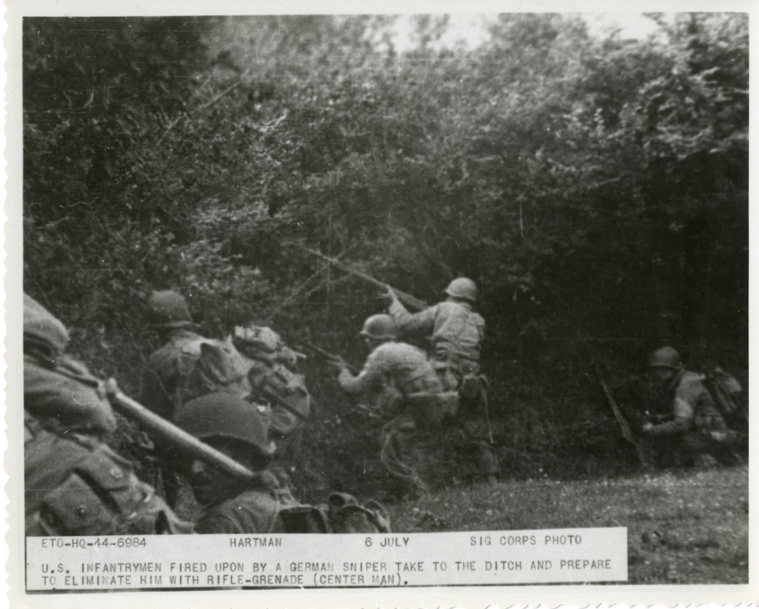 Troops fire on a German sniper. “ETO-HQ-44-6984. Hartman. 6 July. Signal corps photo. U.S. infantrymen fired upon by a German sniper take to the ditch and prepare to eliminate him with rifle-grenade (center man).” Northern France. 6 July 1944. [3600×2889]